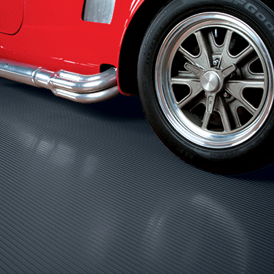 Ribbed garage mat in slate grey shown with a partial view of a sports car on the mat for illustrative purposes