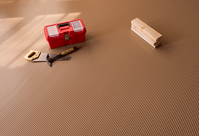 Ribbed channel garage mat shown in sandstone with hand tools on the mat for illustrative purposes