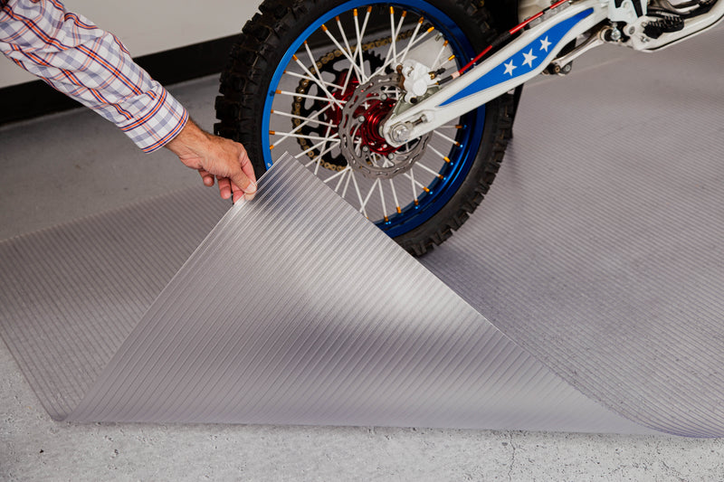Hand holding corner of clear Ribbed texture vinyl motorcycle mat