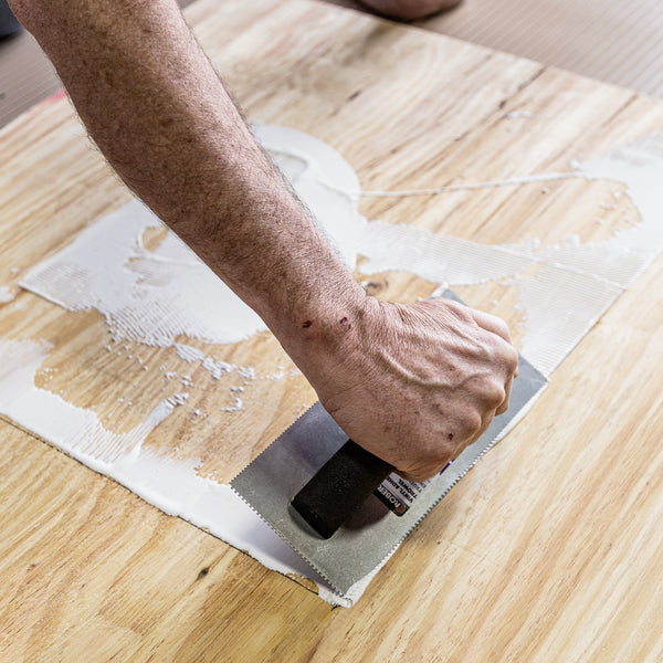 Arm applying adhesive to wood with trowel
