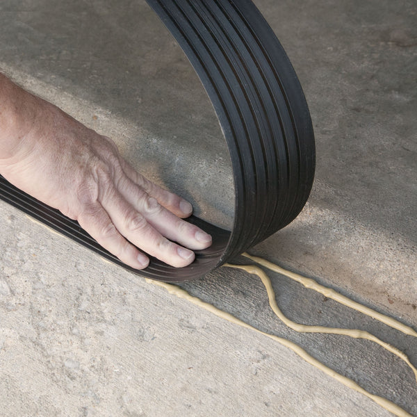 Hand applying vinyl threshold onto concrete with adhesive