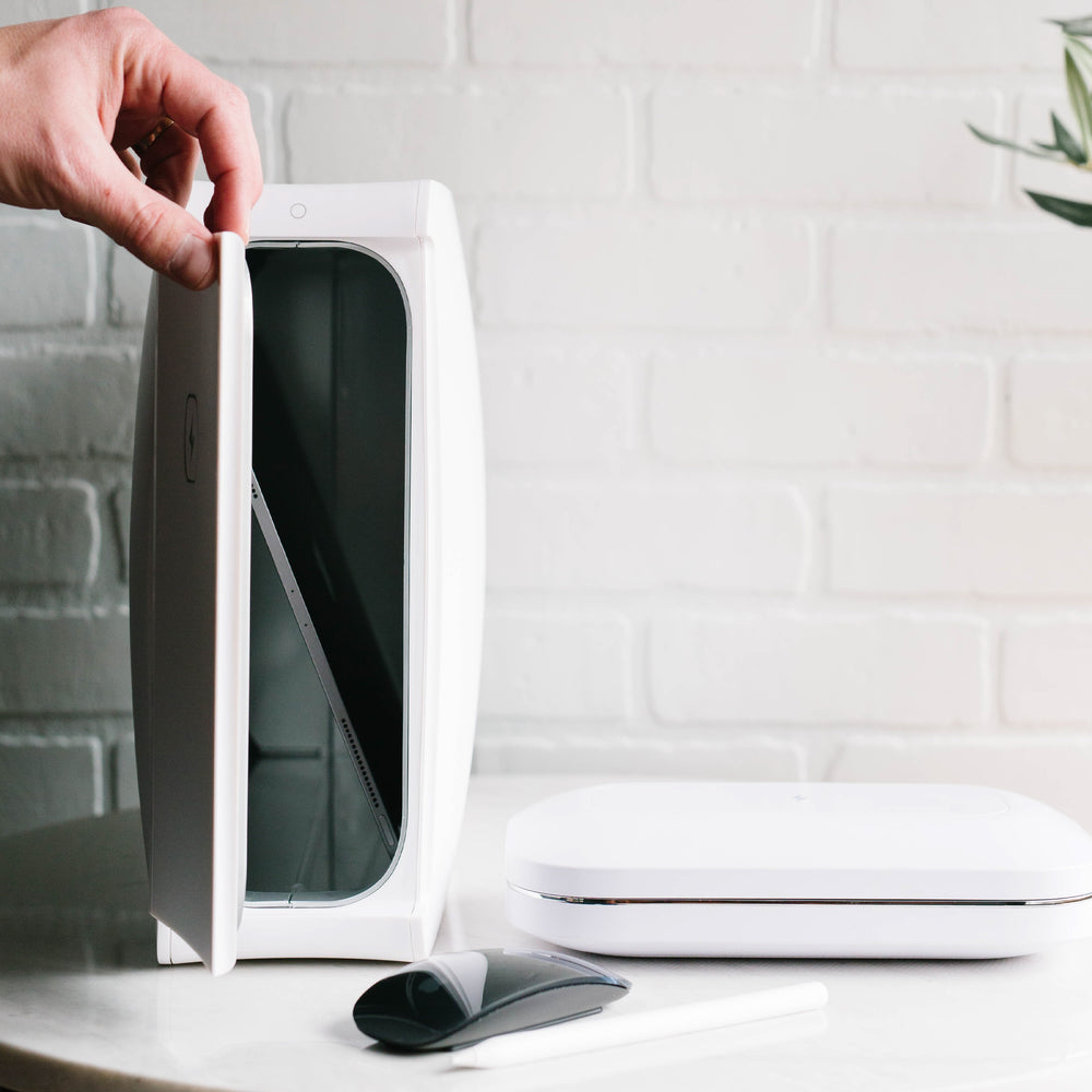 Hand holding door to homesoap device open with white phonesoap next to it
