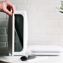 Hand holding door to homesoap device open with white phonesoap next to it