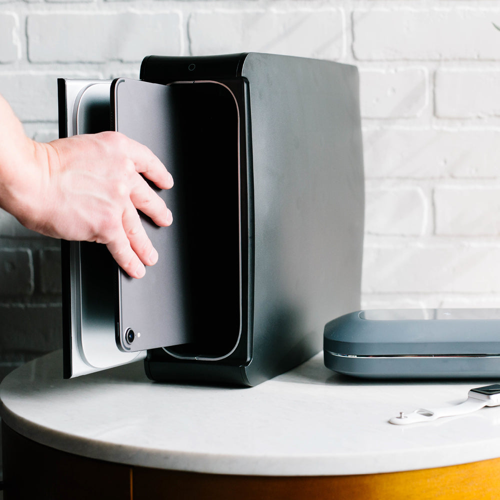 Hand holding door to homesoap device open with white phonesoap next to it