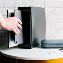 Hand putting tablet into black Homesoap device with phonesoap next to it